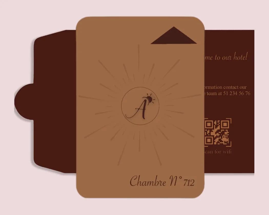 The caramel key card in front of the holder: an A monogram at the centre of a sun motif and the words Chambre N° 712.